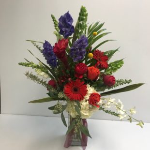 Seasons Breeze flower arrangement with Blue Delphinium, Gerbera Daisies, Hydrangea, Lily, Red Roses, White Orchid