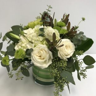 Pure Elegance flower arrangement with roses and lilies arranged in a unique vase alongside protea, eucalyptus, and a variety of other greens